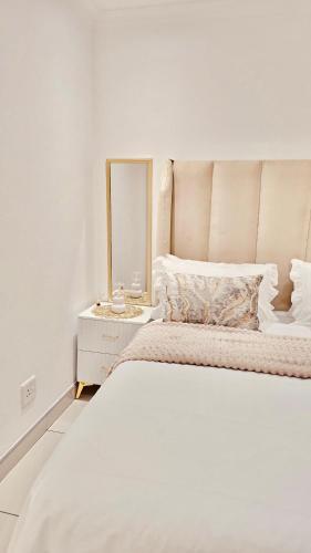 a white bedroom with a bed and a mirror at Beautiful Luxury Apartment in Johannesburg
