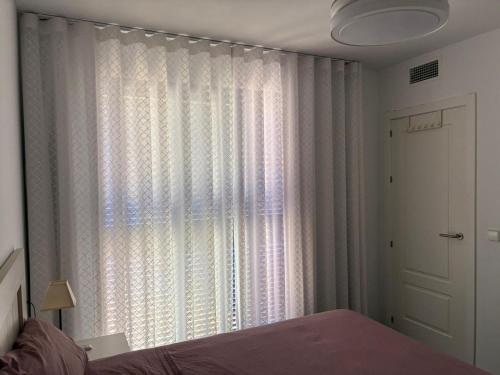 a bedroom with a bed and a window with curtains at Apartamento de lujo, para relajarse en Mojácar in Mojácar