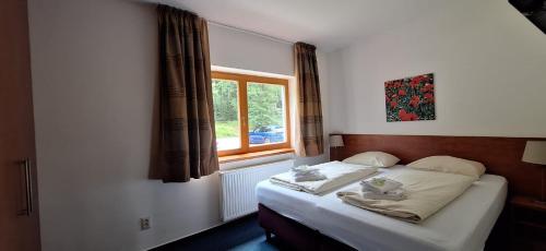 a bed in a bedroom with a window at Prémiový apartmán s privátní saunou a terasou v blízkosti Lipenské nádrže a lyžařského střediska in Lipno nad Vltavou