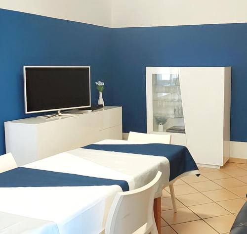 a blue room with two beds and a flat screen tv at Casa Granata in Trapani