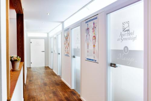 a hallway with white walls and wood floors and posters at Apart Hotel am Sonnenhügel in Bad Birnbach