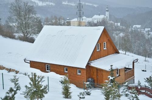a wooden barn with snow on the roof at Penzion Na Vršku in Branná