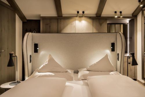 a bedroom with a white bed with two pillows at Brugger's Genießerhotel Lanersbacherhof in Tux
