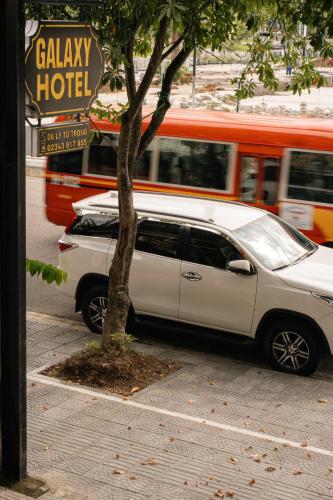 a white car parked next to a tree on a street at Galaxy Hotel in Hue