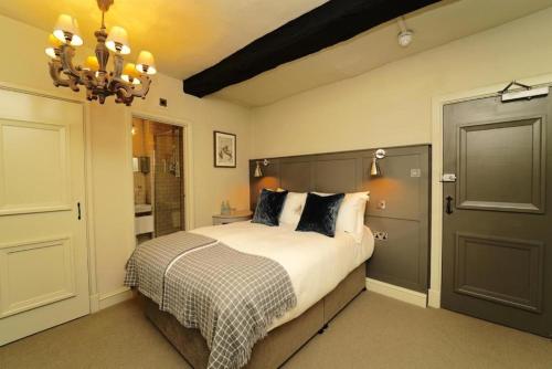 a bedroom with a bed and a chandelier at The Bull Hotel in Fairford