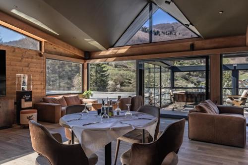 a dining room with a table and chairs and large windows at Grand Chamois Hotel & Spa in Mavrovo