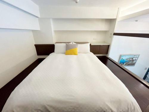 a bedroom with a white bed with a yellow pillow at 湯韻溫泉 in Jiaoxi