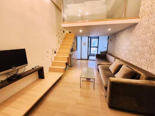 a living room with a couch and a tv and stairs at 湯韻溫泉 in Jiaoxi