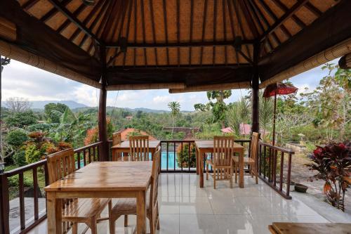 a patio with tables and chairs on a balcony at Kampuak Cottages in Nusa Penida