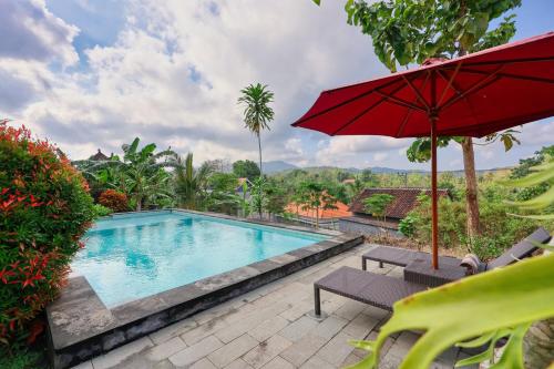 a pool with a red umbrella and chairs and a table with at Kampuak Cottages in Nusa Penida