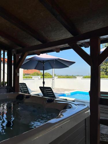 a hot tub with two chairs and an umbrella at Holiday House Renata in Kutina
