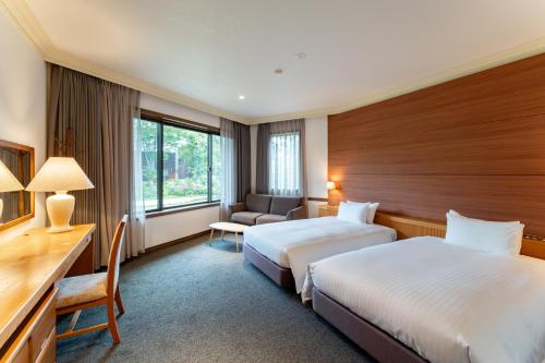 a hotel room with two beds and a desk at Hotel Sierra Resort Hakuba in Hakuba