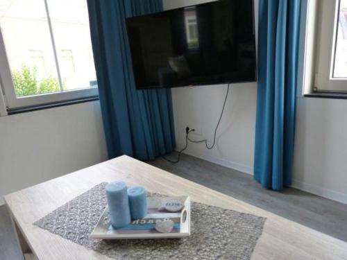 a living room with a table with a television and blue curtains at Rural holiday home with terrace in Breskens