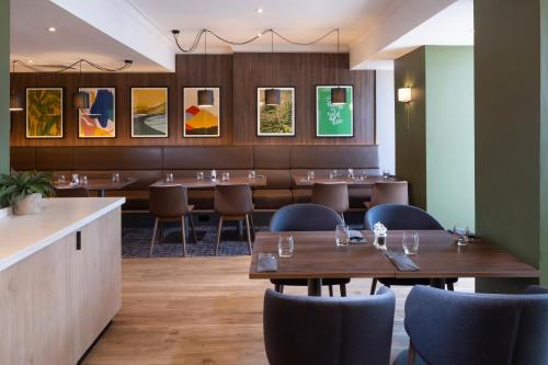 a restaurant with tables and chairs and paintings on the wall at Holiday Inn Farnborough by IHG in Farnborough