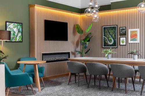 a dining room with a table and chairs and a television at Holiday Inn Farnborough by IHG in Farnborough