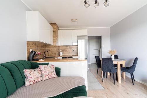 a living room with a green couch and a kitchen at Apartament MOJA MŁYNOWA in Białystok