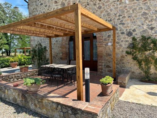 a wooden pavilion with a table and chairs in front of a building at Agriturismo La Peschiera in Casole dʼElsa