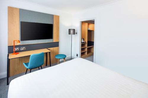 a hotel room with a bed and a flat screen tv at Holiday Inn Farnborough by IHG in Farnborough