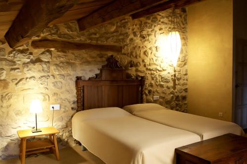 a bedroom with a bed in a stone wall at Poble Rural Puig Arnau - Pubilló in Oden