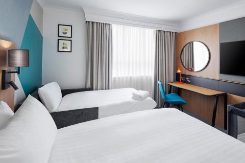 a hotel room with two beds and a mirror at Holiday Inn Farnborough by IHG in Farnborough