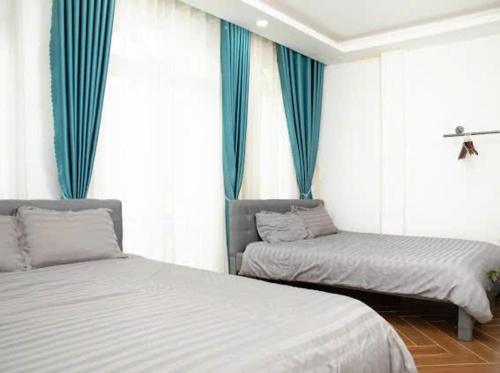 a bedroom with two beds and blue curtains at LALA HOUSE - CĂN HỘ Đà Lạt in Khu Chi Lăng