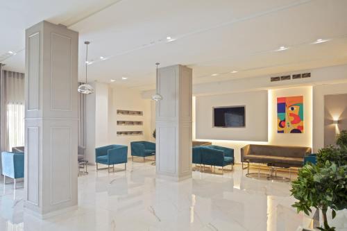 a lobby with blue chairs and a couch and a tv at Hotel Donia Sfax in Sfax