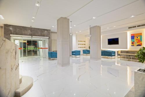 a lobby with white marble floors and blue chairs at Hotel Donia Sfax in Sfax