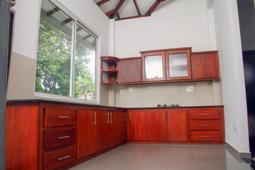 a kitchen with wooden cabinets and a window at Lotus Villa in Katunayake
