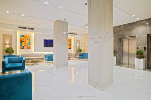 a lobby with blue chairs and tables in a building at Hotel Donia Sfax in Sfax