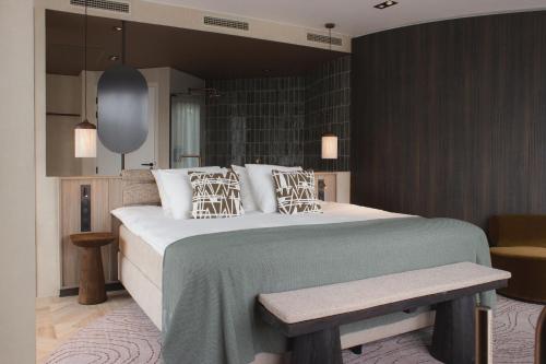 a bedroom with a large bed and a bench at Wellnesshotel Thermae 2000 in Valkenburg