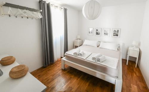 a white bedroom with a bed and a mirror at Apartments Marijin Dvor in Splitska