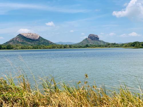 a large body of water with mountains in the background at Sigiri Village Vibe Hostel in Sigiriya