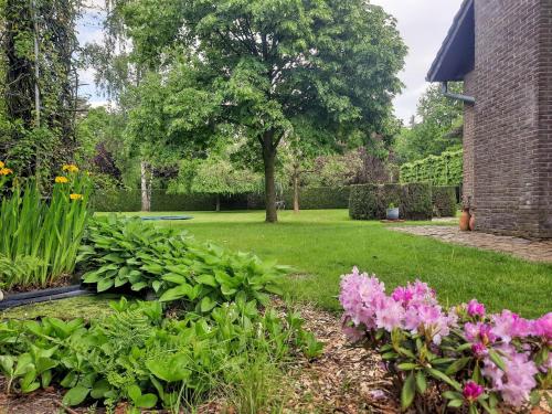 a garden with flowers and a brick building at Merksplas Villa with Terrace in Merksplas