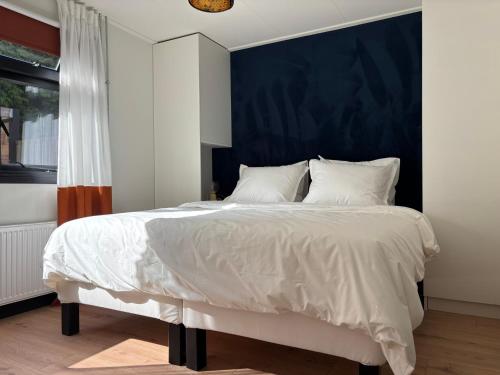 a bedroom with a large bed with a blue headboard at Huisje van Hans in Ermelo