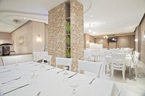a dining room with white tables and white chairs at Hotel Donia Sfax in Sfax