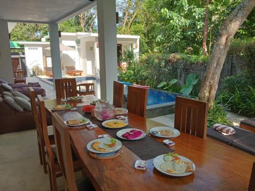 een houten tafel met borden met eten erop bij Villa Collard in Senggigi 
