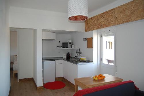 una pequeña cocina con armarios blancos y una mesa en Casa Das Gaivotas, en Sesimbra