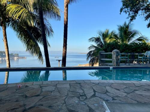 a swimming pool with palm trees and the ocean at Lake Kariba Inns in Siavonga