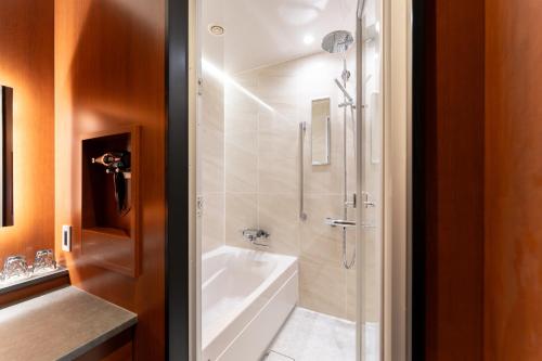 a bathroom with a shower and a white bath tub at Hotel Sierra Resort Hakuba in Hakuba