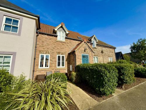 a brick house with a blue door at Sunset Cottage - Part of the The Bay Filey Holiday Village with pool, gym and direct beach access, pub, restaurant, tennis and meadows walks in Filey