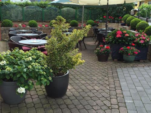a patio with tables and chairs and potted plants at Gästehaus Mack in Trittenheim