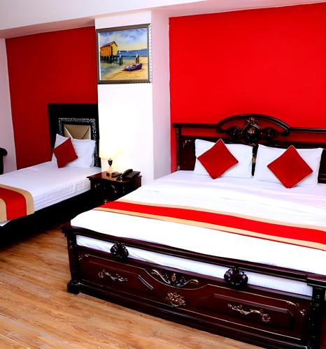 two beds in a room with red walls at Premier Inn Heights hotel Davis Road Lahore in Lahore