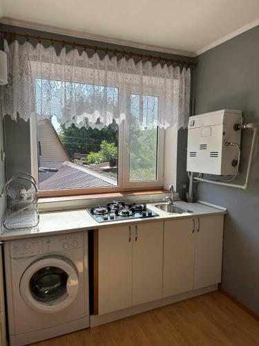 a kitchen with a washing machine and a window at Домик у моря в Фонтанке in Odesa