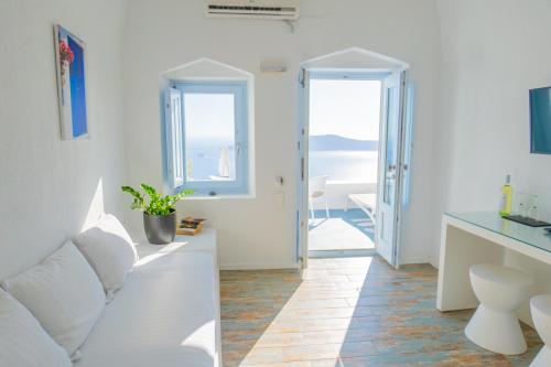 a white living room with a white couch and a window at Sunset Caldera Seaview Houses in Imerovigli