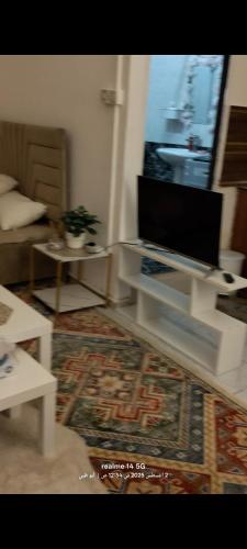 ein Wohnzimmer mit einem TV, einem Tisch und einem Sofa in der Unterkunft المناصير in Abu Dhabi