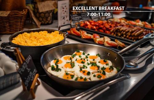 a buffet with two pans of eggs and other food at Cosmopolitan Bobycentrum - Czech Leading Hotels in Brno