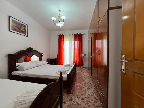 a bedroom with two beds with red curtains and a door at Kevi City Center Apartments in Përmet