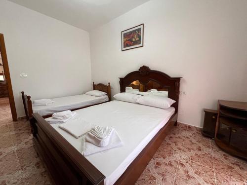 a bedroom with two beds with white sheets and a piano at Kevi City Center Apartments in Përmet