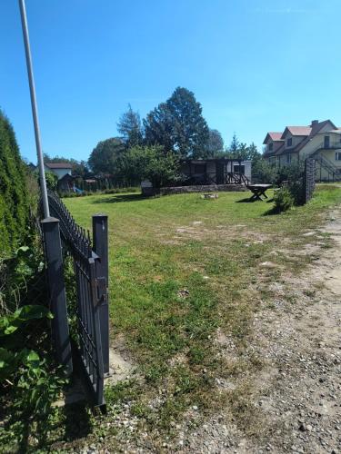 a black fence in a field with houses in the background at Leśna Aura in Ponizie