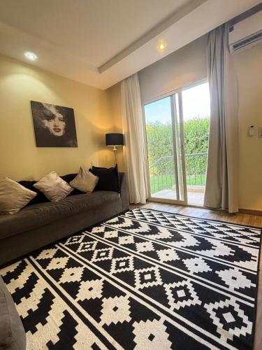 Una sala de estar con un sofá y una ventana grande. en Zayed Elite Retreat pool, garden & breeze, en Seis de Octubre